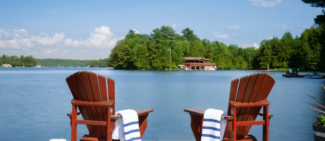 CottageeCountryAlt Red Muskoka chairs overlooking a lakeside dock representing Lux Furniture Rentals' Cottage Country delivery service area.