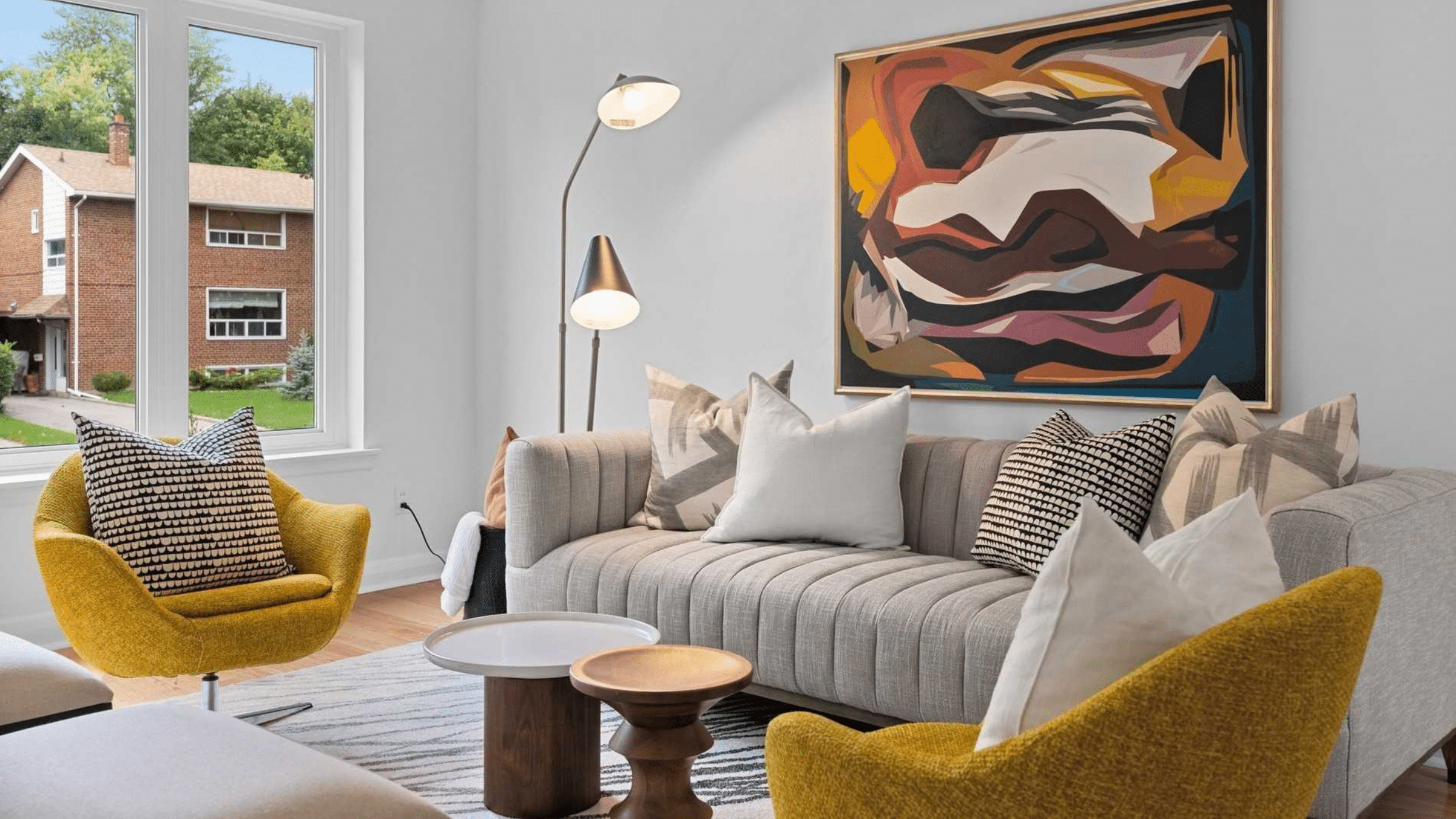 Contemporary living room with grey sofa, mustard accent chairs, sculptural coffee tables and abstract artwork