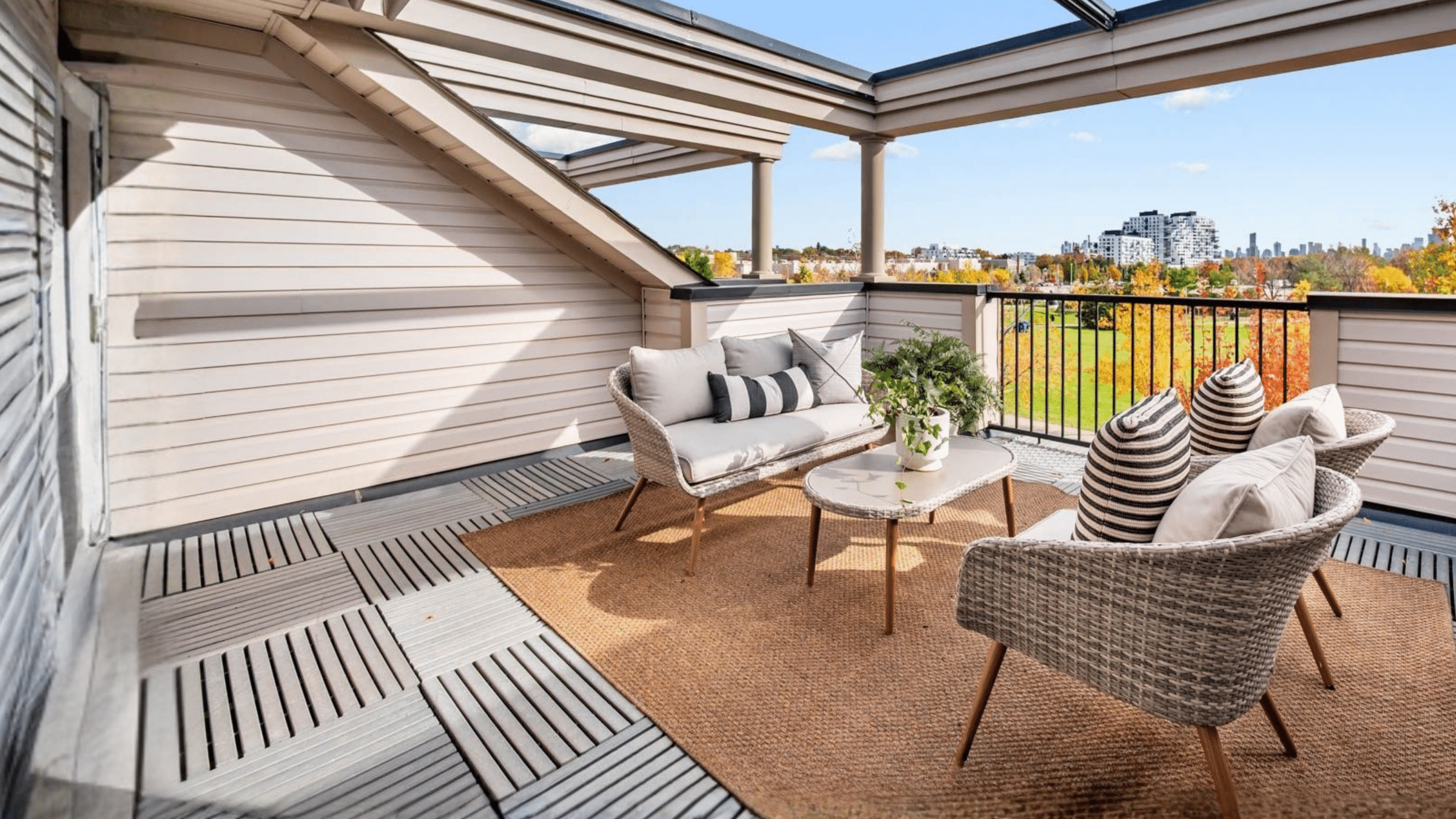 Stylish outdoor terrace with woven seating, striped cushions, coffee table, area rug and views over the city